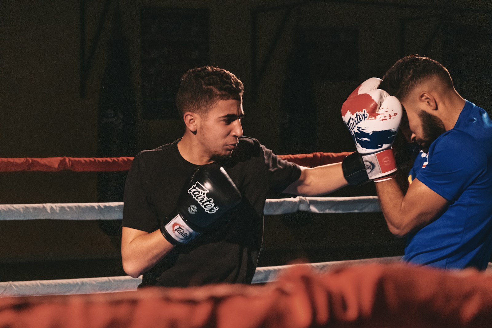 man in black crew neck t-shirt wearing red boxing gloves